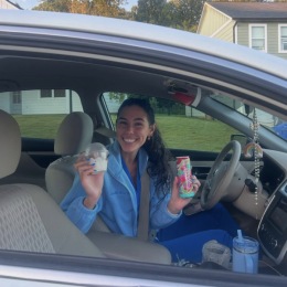 a woman posing in her vehicle with a drink in hand