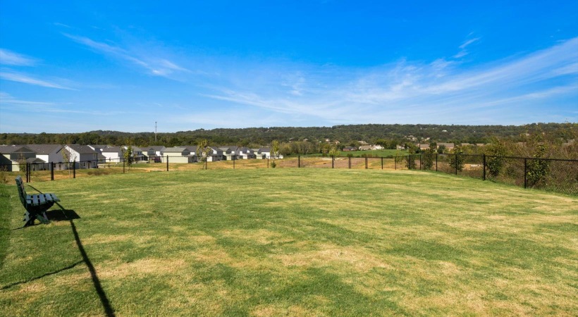 a large grassy field with houses in the background